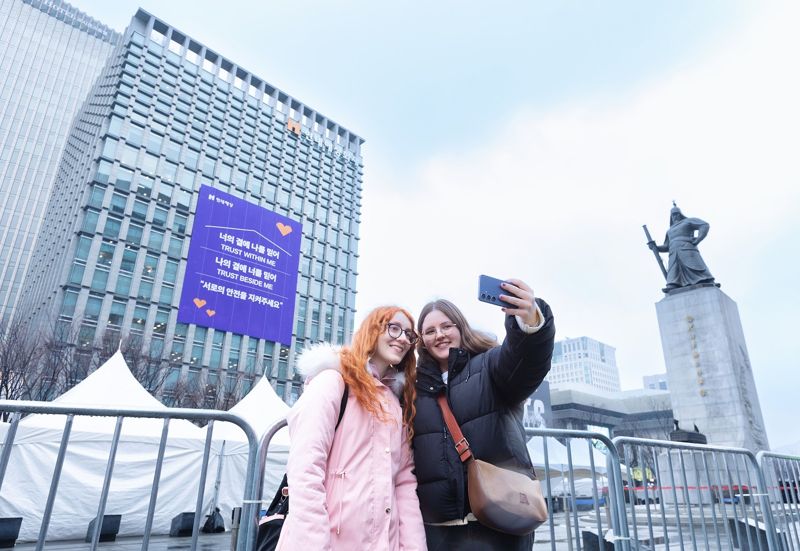 18일 서울시 종로구 현대해상 본사 외벽 방탄소년단의 노래 가사를 인용한 ‘신뢰와 안전’ 메시지를 배경으로 외국인 방문객들이 사진을 촬영하고 있다. 현대해상 제공