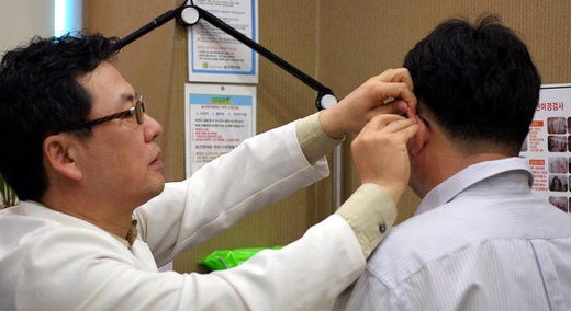 동인한의원 김호선 원장(왼쪽)이 환자에게 귀에 경혈을 자극하는 이침 치료를 하고 있다.