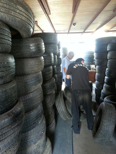 경기도 고양시에 위치한 중고타이어 매장 내부 모습. 매장 안은 중고타이어들로 꽉 차 있다. 택시운전기사(뒤)가 중고타이어 구매를 위해 타이어 상태를 확인하는 모습이다.