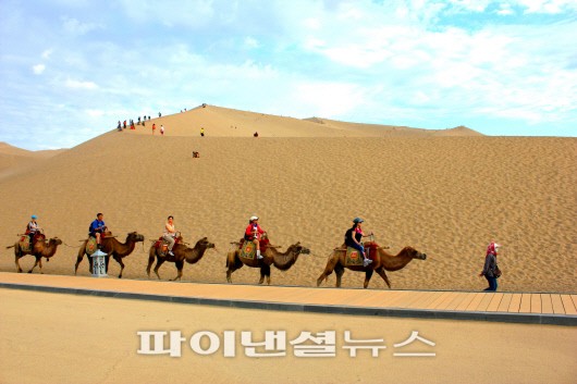 명산산의 모래는 마치 파우더처럼 곱디 곱다. 낙타를 탄 관광객들이 명사산을 가로질러 가고 있다.
