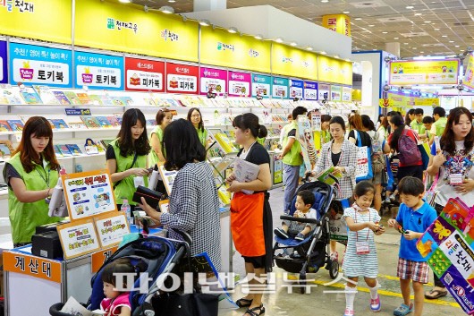 전시회장에 마련된 천재교육 부스를 아이와 함께 찾은 학부모들이 도서 제품을 관심 있게 살펴보고 있다.