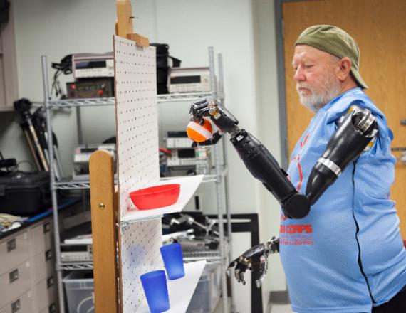 로봇팔을 이식받은 레슬리 보가 자신의 의지대로 의수를 조정해 선반위의 공을 집어 다른 위치로 옮기는 작업을 수행하고 있다. 사진=Johns Hopkins University Applied Physics Laboratory