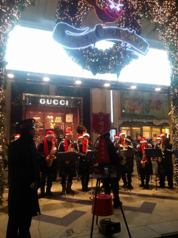 크리스마스 이브를 하루 앞둔 23일, 서울 남대문로 롯데백화점 본점 앞에서 구세군 냄비 관계자들이 캐롤을 연주하고 있다. 반면 롯데·신세계백화점 등 건물 안에서는 크리스마스 캐롤이 들리지 않아 대조를 이뤘다.