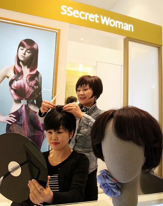 신세계 센텀시티 2층에 위치한 헤어웨어 전문업체 '씨크릿 우먼'을 찾은 한 고객이 직원을 통해 가발을 착용해보고 있다.