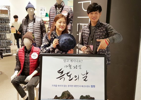 신세계 센텀시티 8층 탑텐 매장 직원들이 독도문양 경량 다운재킷과 국방무늬 후리스자켓, 모자 등을 선보이고 있다.