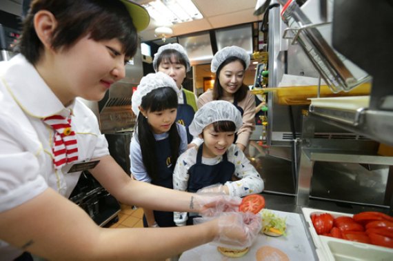 내셔널 오픈 데이 진행 첫날인 20일, 맥도날드 서울 관훈점에서 열린 행사에 참여한 주부 고객과 어린이들이 햄버거가 만들어지는 과정을 지켜보고 있다