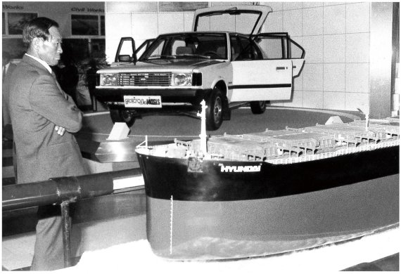 1980년대 초 한국종합전시장(KOEX)에 전시된 포니2 모델과 선박 모형 앞에 서있는 정명예회장.