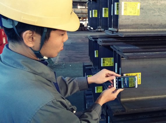 동국제강 직원이 H형강에 부착된 스마트 라벨의 QR코드를 스마트폰으로 인식하고 있다.
