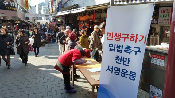 영하권의 쌀쌀한 날씨속에도 한 상인이 16일 서울 남대문시장에 마련된 민생구하기 입법 촉구 서명대에서 서명을 하고 있다.