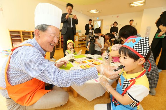 허창수 전경련 회장(왼쪽)이 23일 제1호 안산 보듬이나눔이어린이집을 방문해 일일 보육교사 봉사활동을 했다. 허 회장이 한 어린이에게 김밥을 먹여주고 있다.