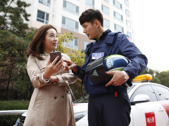 에스원 출동요원이 여성고객에게 개인 보안서비스를 제공하는 '안심모바일' 사용법을 설명하고 있다.