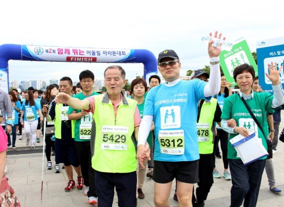 SC제일은행 임직원 160여명은 지난 3일 서울 여의도 한강공원 이벤트광장에서 열린 ‘시각장애인돕기 함께 뛰는 어울림마라톤대회’에 참여해 시각장애인 손을 잡고 화이팅을 외치고 있다. 이들은 마라톤 참가비 전액을 시각장애인 돕기 활동에 기부했다.