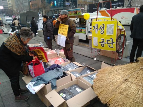 CNGN 직원들이 지난 11일 서울 세종대로 광화문광장에서 열린 촛불집회에 나와 개성공단에서 제작된 의류를 판매하고 있다.