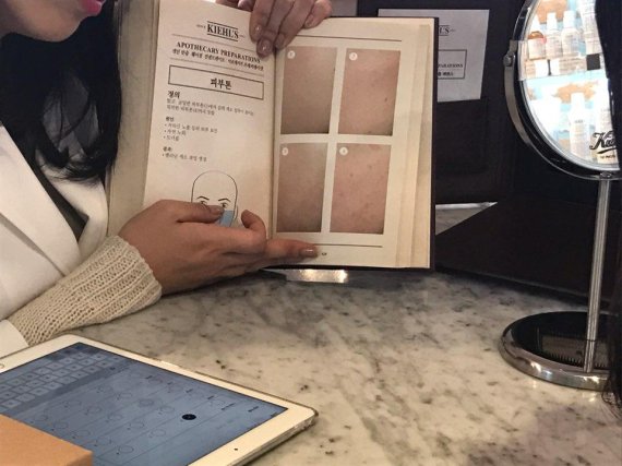 키엘 삼청동 매장에서 키엘의 전문 상담원 이 '스킨 아틀라스'라는 피부 상태 체크용 북을 사용해 고객의 피부 고민을 상담해 주고 있다.