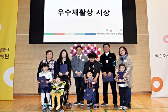 넥슨코리아 강민혁 대외정책이사(뒤쪽 왼쪽 세번째)가 '우수 재활참여상'을 받은 환아 및 부모들과 기념촬영을 하고 있다.