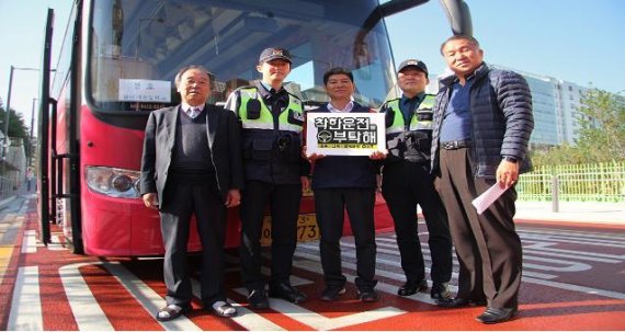 26일 서울 금천구 금나래초등학교 앞에서 이 학교 수학여행 버스기사와 금천경찰서 경찰관이 '착한운전을 부탁해' 피켓을 들고 포즈를 취하고 있다.