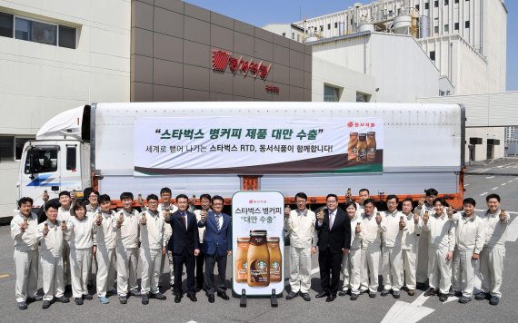 충북 진천의 동서식품 진천공장에서 열린 스타벅스 병커피 대만수출 기념식에서 동서식품 임직원들이 대만으로 수출할 제품을 실은 트럭을 배경으로 기념촬영을 하고 있다.