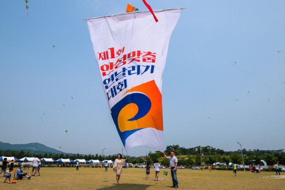 강규원 안성시청소년문화의집 국장(오른쪽)과 하영란 안성시립남사당바우덕이풍물단 상임단원이 지난 17일 경기 안성시 안성맞춤랜드에서 열린 '제1회 하늘축제 안성맞춤 연날리기대회에서 봉황창작줄 연에 매달린 대형 현수막을 올리고 있다. 봉황창작울 연은 조선시대 유일의 전통연 '방패연'의 원형기법을 우리나라에서 유일하게 보유하고 있는 리기태 명장이 만들었다.