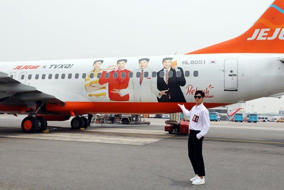 동방신기의 유노윤호가 지난 19일 SM엔터테인먼트 제주워크숍을 떠나기 전 자신의 얼굴이 래핑된 제주항공 래핑기를 배경으로 사진촬영을 하고 있다./사진=fnDB