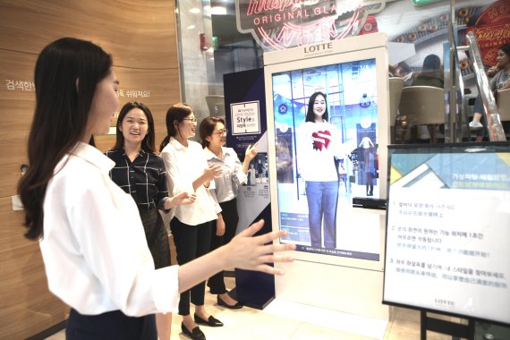 서울 소공동 롯데백화점 본점에서 한 고객이 직원들의 안내를 받아 3차원(3D) 가상 피팅 서비스를 이용하고 있다. 3D 가상 피팅 서비스는 디지털 거울과 스마트폰을 활용해 옷을 입어보지 않아도 편리하고 재미있게 피팅 결과를 확인할 수 있는 서비스다.