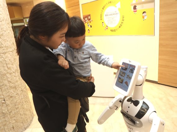 서울 소공동 롯데백화점 본점에서 한 고객이 자율주행하는 안내로봇 '엘봇'에게서 맛집을 추천받고 있다.