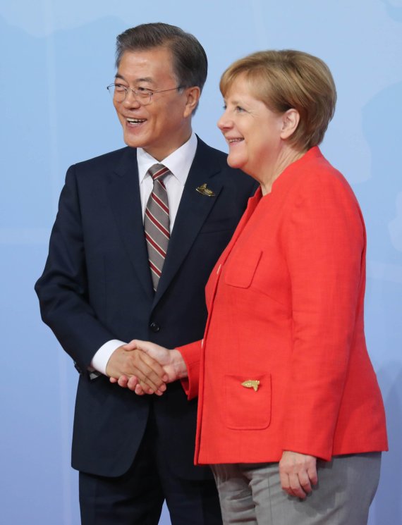 문재인 대통령이 지난해 7월 7일 오전(현지시간) 독일 함부르크 G20 정상회의장 메세홀에서 열린 공식환영식에 입장하며 주최국인 독일 앙겔라 메르켈 총리과 악수를 하고 있다. 연합뉴스