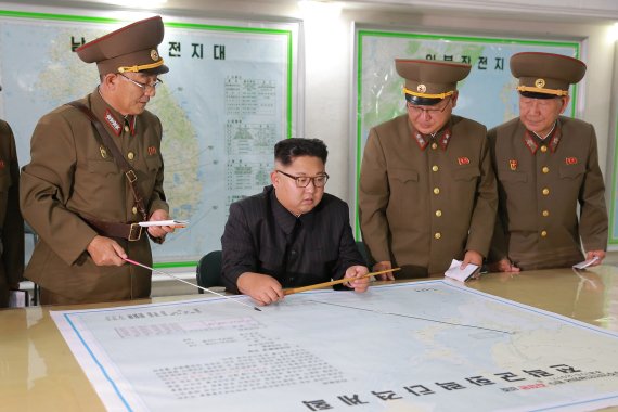 김정은 북한 노동당위원장(왼쪽에서 두번째)이 지난 14일 전략군사령부를 시찰하면서 김락겸 전략군사령관으로부터 '괌 포위사격' 방안에 대한 보고를 받고 있다. 연합뉴스