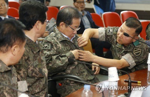 자유한국당 홍준표 대표가 22일 오전 강원 홍천군 육군 11사단을 방문해 박주경 사단장의 도움을 받아 전투복으로 갈아입고 있다.
