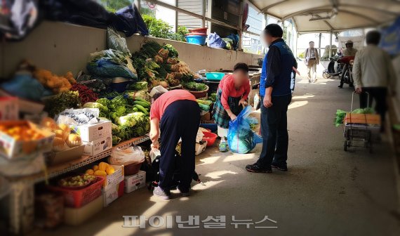 ▲ 동작구청 가로정비 직원의 단속에 따라 할머니 상인이 진열대를 정비하고 있다.