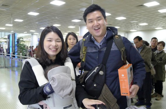 18일 울산공항에 취항한 제주항공 첫 탑승객이 제주로 출발하기 전 항공사측이 제공한 기념품을 받고 포즈를 취하고 있다.