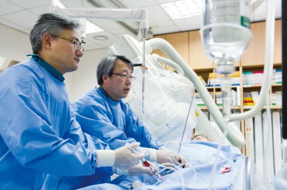 강동성심병원 심장혈관센터 한규록 센터장(오른쪽)이 관상동맥이 막힌 환자에게 요골동맥을 이용해 관상동맥 중재시술을 하고 있다.