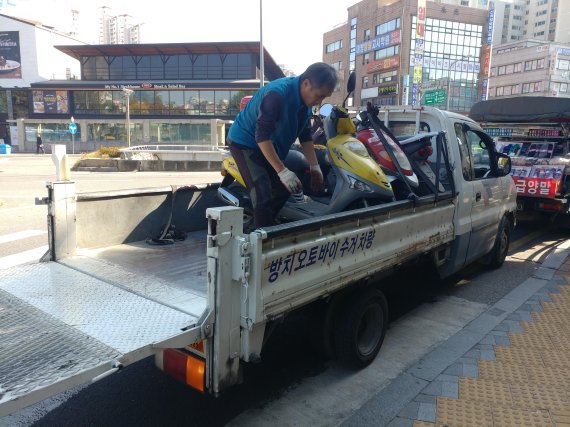 지난 25일 서울 영등포구에서 한 방치 차량 수거 직원이 무단으로 방치된 이륜차를 수거하고 있다. /사진=김유아 기자