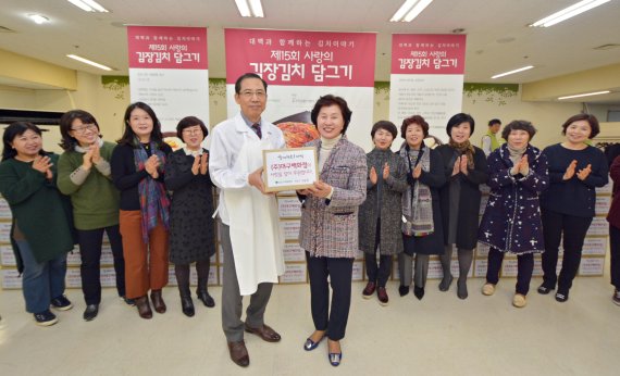 최관웅 대구백화점 사장(앞줄 왼쪽)이 유영은 대구YWCA 회장에게 김장김치를 전달하고 있따.