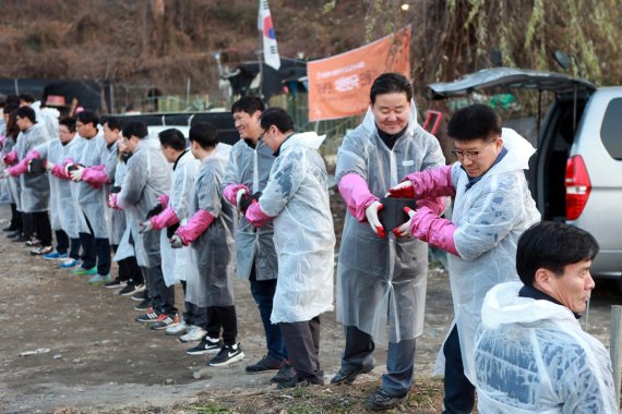 휴비스 신유동 대표이사(오른쪽 세번째)와 임직원들이 지난 22일 서울 서초구 방배동 전원마을 일대에서 '희망키움 연탄배달' 봉사 활동에 나서 연탄을 옮기고 있다. /사진=fnDB