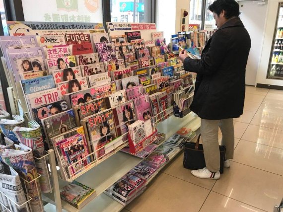 일본 세븐일레븐 편의점 신문 잡지 코너에서 한 남성이 잡지 책을 구입하기 위해 살펴보고 있다. /사진=fnDB