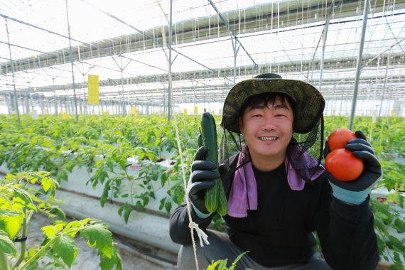 충청남도 논산 광석면에 위치한 농업회사법인 팜팜의 양광식 대표가 비닐 온실에서 주요 생산품인 오이와 토마토를 들고 포즈를 취하고 있다. 팜팜은 신세계푸드와 계약재배를 통해 전체 농산물 생산량의 80%를 안정적으로 판매하고 있다.