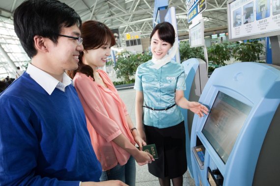 대한항공 승무원이 인천국제공항에서 탑승권 자동발급기인 '키오스크(Kiosk)'를 이용해 셀프체크인을 하는 방법을 안내하고 있다.