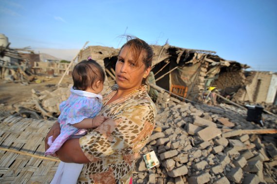 페루 아레키파주 베야우니온에서 14일(현지시간) 현지 여성이 아기를 안고 무너진 집 앞에 서 있다.로이터연합뉴스