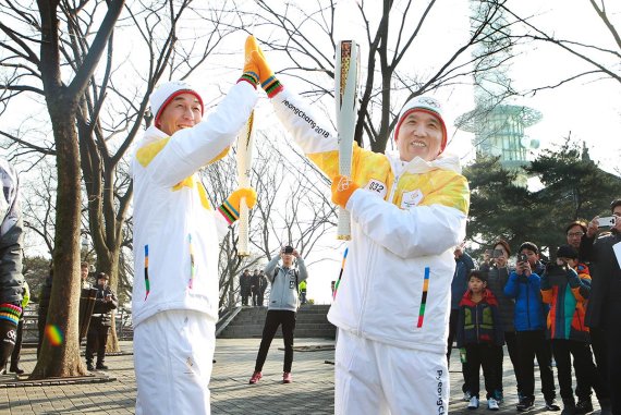 함영주 KEB하나은행장(오른쪽)과 서홍석 (주)삼천리기계 대표(왼쪽)가 2018 평창동계올림픽 성화봉송 행사에 참여해 평창동계올림픽 성공을 기원하는 하이파이브를 하고 있다.