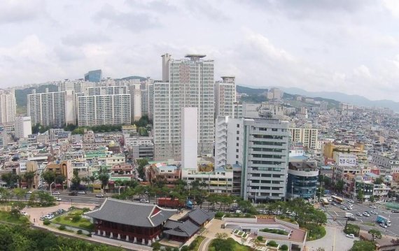 울산 중구 리버스위트 주상복합아파트(사진 중앙) 최저임금 인상에도 불구하고 입주민들이 주민투표를 통해 감원없이 경비원과 미화원들의 임금인상분 만큼 관리비를 인상해 화제를 모으고 있는 울산 중구의 리버스위트 주상복합아파트다. 이 아파트는 지난 2016년 태풍 차바로 인해 침수피해를 입기도 했지만 주민들은 아랑곳없이 매년 경비원과 미화원의 임금을 인상해 온 것으로 알려지고 있다.