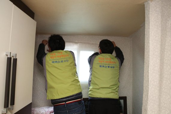 동아제약 박카스 봉사단이 문풍지 및 단열 뽁뽁이 설치를 하고 있다.