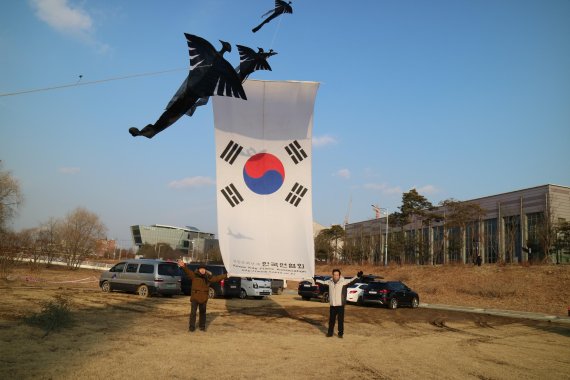 안민석 국회의원과 리기태 명장이 대형태극기를 올리고 있다.