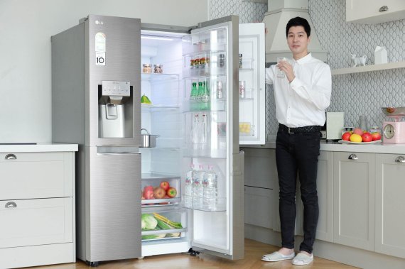 LG전자 모델이 얼음정수기를 탑재한 2018년형 LG 디오스 양문형냉장고를 소개하고 있다.