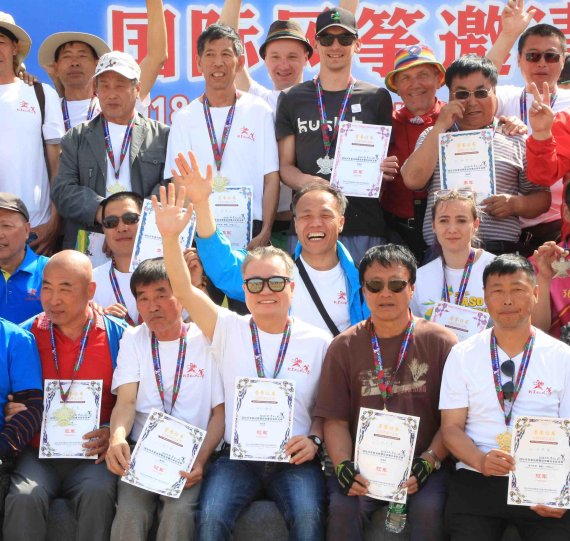 리기태 방패연 명장(첫째 줄 가운데)과 신종욱 선수(둘째 줄 왼쪽 두번째)가 '2018 베이징 국제 연 축제' 수상자들과 사진 촬영하고 있다.