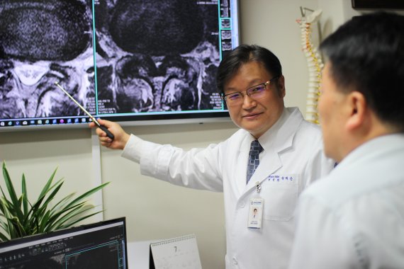 다나은신경외과 정택근 대표원장(왼쪽)이 척추관협착증 환자에게 '단일통로 협착증 내시경 시술'에 대해 설명하고 있다.