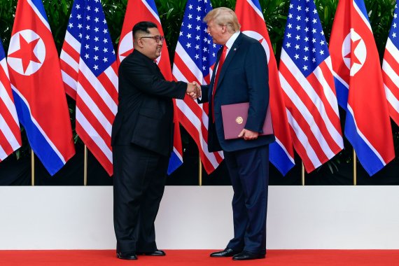 지난 해 6월 12일 싱가포르에서 개최된 1차 북·미정상회담에서 김정은 북한 국무위원장(왼쪽)과 도널드 트럼프 미국 대통령이 합의문에 서명한 뒤 악수를 하고 있다. /사진=연합뉴스
