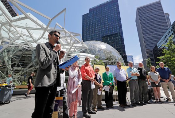 Shankar Narayan, legislative director of the ACLU of Washington, left, speaks at a news conference outside Amazon headquarters, Monday, June 18, 2018, in Seattle. Representatives of community-based organizations urged Amazon to stop selling its face surveillance system, Rekognition, to the governmen