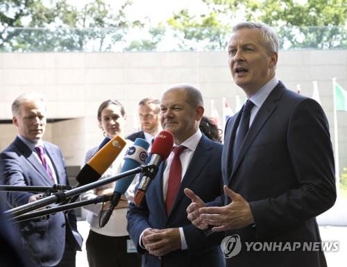 French Finance Minister Bruno Le Maire, right, and German Finance Minister Olaf Scholz, center, speak with the media as they arrive for a meeting of eurogroup finance ministers at EU headquarters in Luxembourg on Thursday, June 21, 2018. Eurozone nations are working on the final elements of a plan t