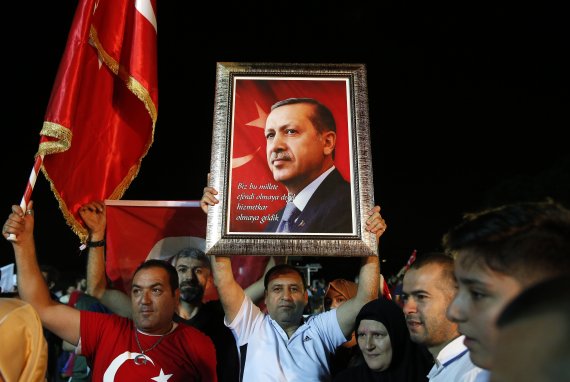 지난 6월 24일 터키 대선 및 총선 당일 이스탄불에 모인 레제프 타이이프 에르도안 대통령의 지지자들이 그의 사진을 들고 에르도안 대통령의 선거 승리 연설을 듣고 있다.AP연합뉴스