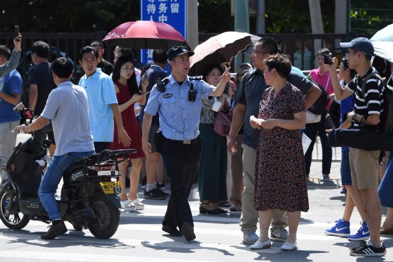 A Chinese police officer (C) gestures among a crowd of bystanders gathered outside the US embassy in Beijing on July 26, 2018 following a blast near the embassy premises.A loud blast occurred near the US embassy in Beijing on July 26, according to multiple eyewitness reports on social media. / AFP P